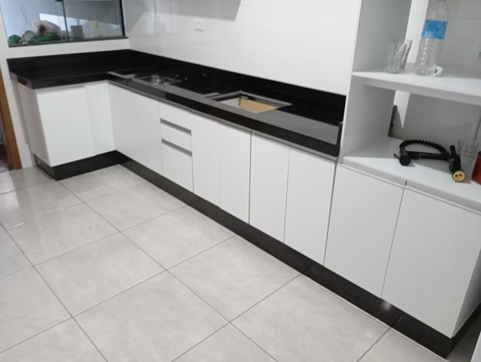 Cozinha com bancada em granito preto e armários brancos