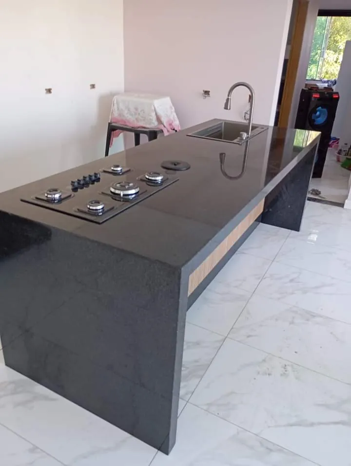 Ilha de cozinha em granito cinza com cooktop e cuba