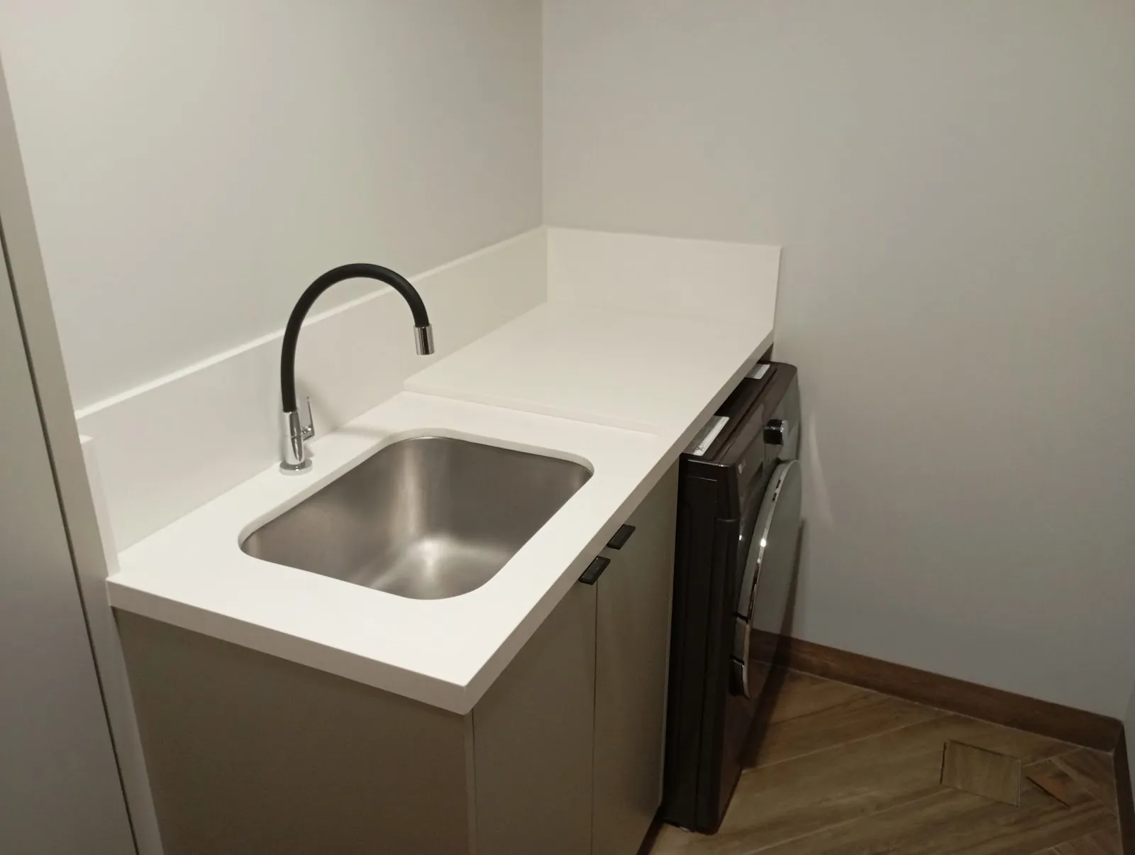 Bancada branca de lavanderia com cuba de inox
